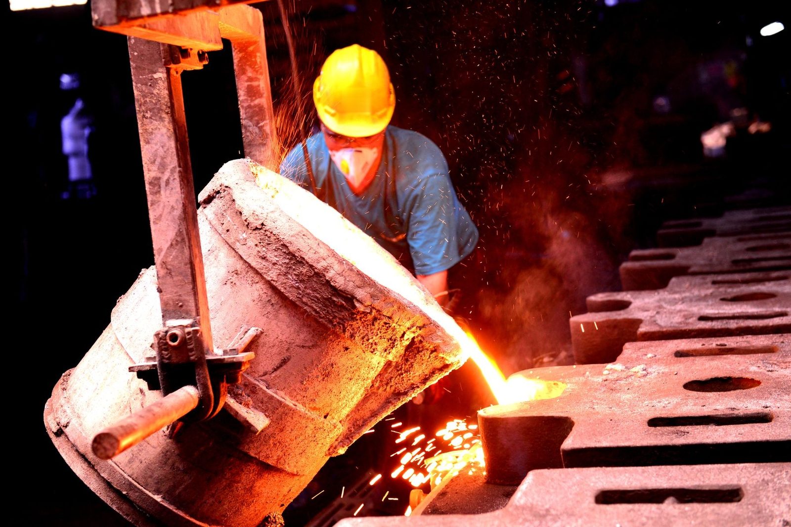 Molten iron poured from a ladle into sand moulds
