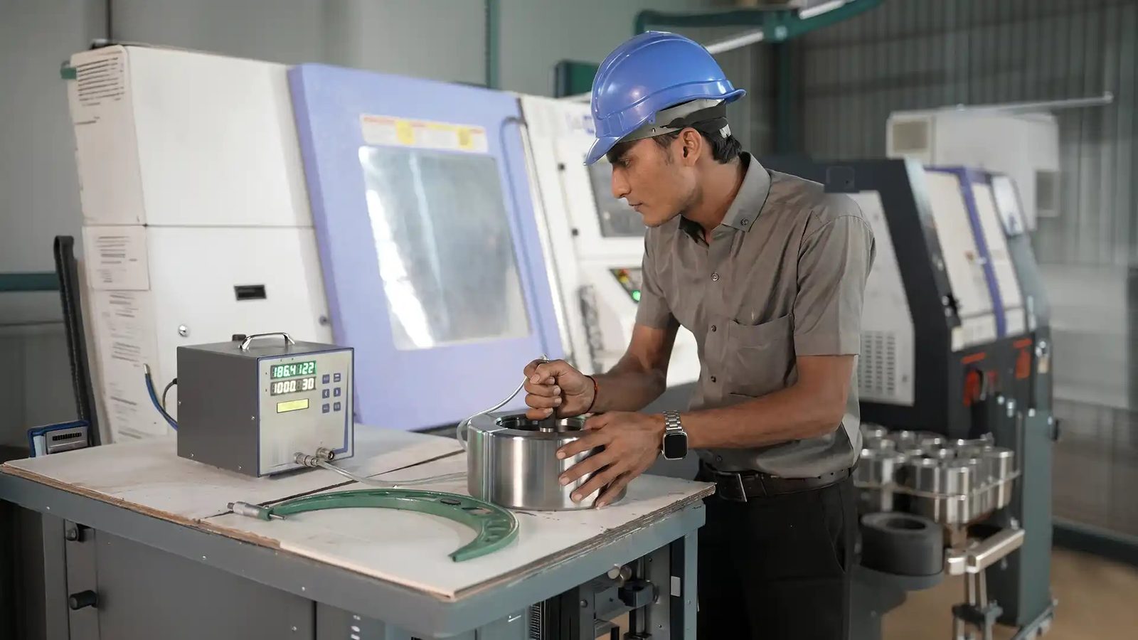 An operator measuring a machined ring beside CNC lathes