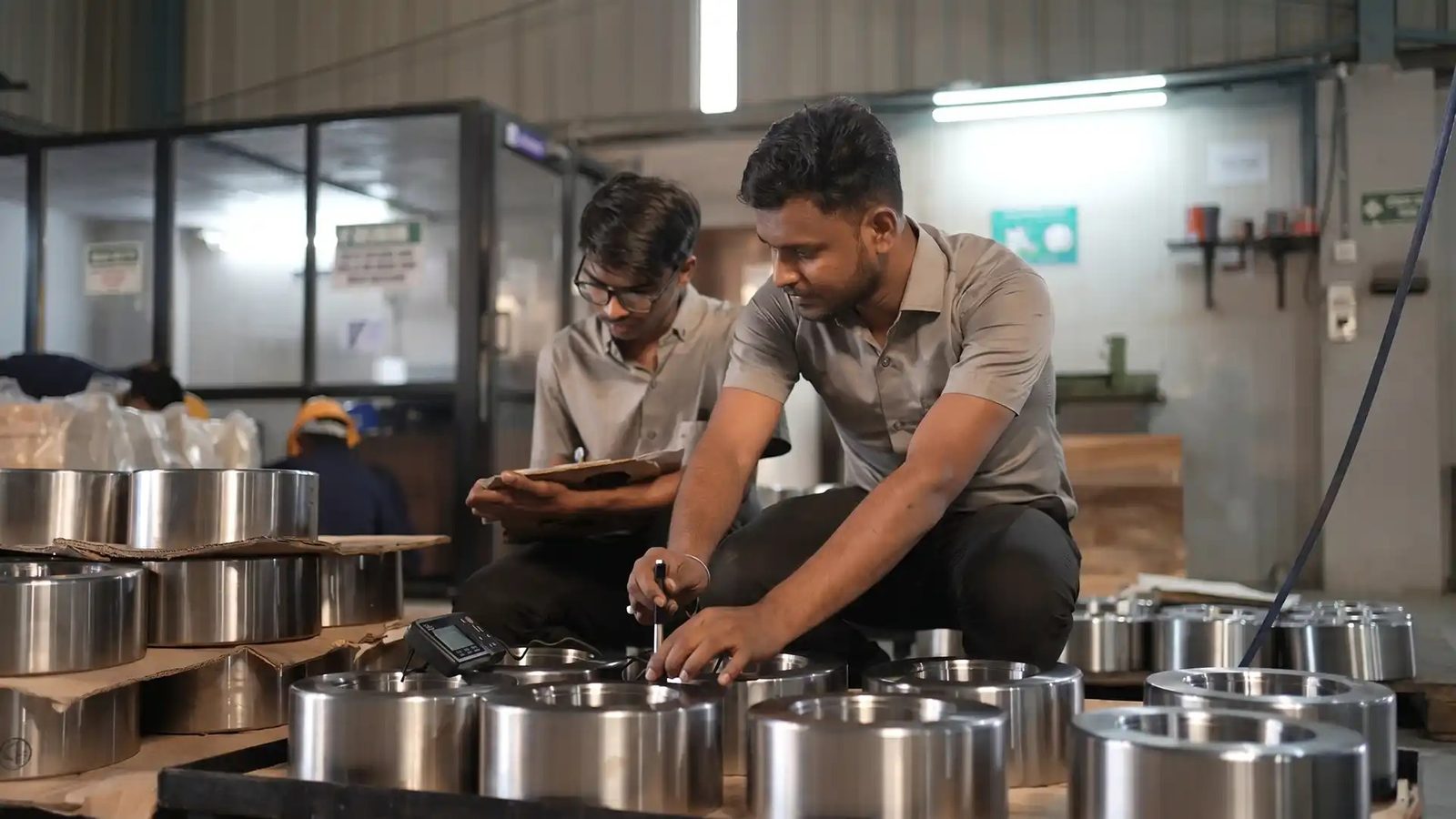 Two inspectors checking machined rings and noting the results